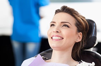 young woman smiling in dental chair after periodontal therapy