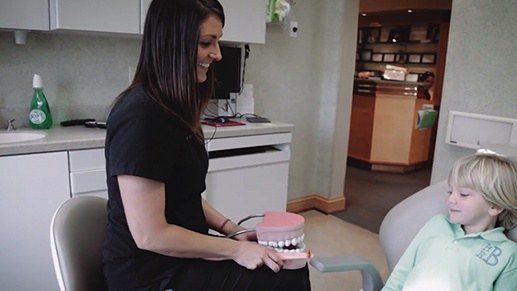 Dental assistant talking to child in dental chair