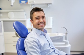 Male dental patient sitting in chair and smiling