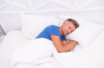 Man sleeping well in white bed linens