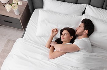 Couple sleeping peacefully together in white bedding