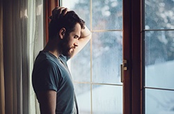 Sad man standing at a window