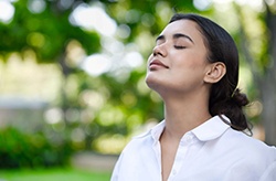 Woman standing outside and taking a deep breath