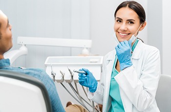 Dentist in white coat smiling before conducting dental exam