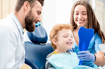 Child smiling in mirror after getting metal-free filling