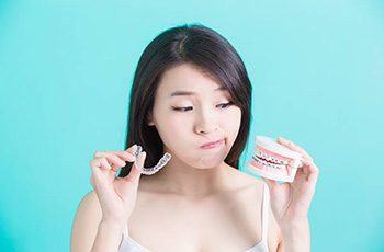 Woman looking at ClearCorrect tray and model smile with braces