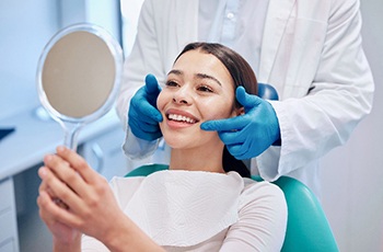 Young woman smiling at reflection in handheld mirror