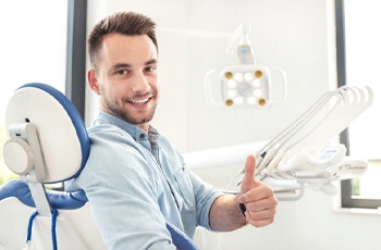 man giving thumbs up in dental chair