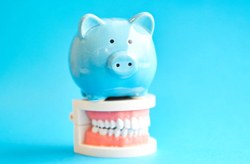 blue piggy bank sitting on model of teeth