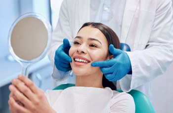 Female dental patient seeing her smile in a handheld mirror