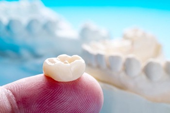 closeup of a dental crown on a dentist’s finger