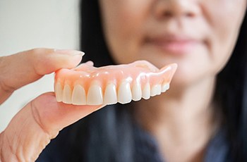 A woman holding a removable denture in her hand