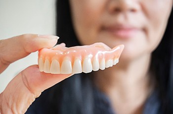 A woman holding a removable denture in her hand