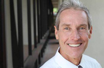 Man sharing confident smile after done in one dental implant denture