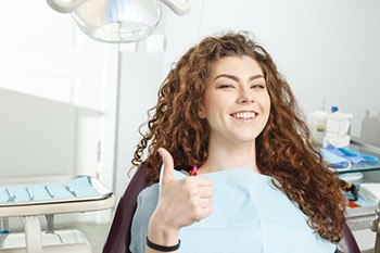 young woman giving thumbs up before getting tooth extractions in Columbia 
