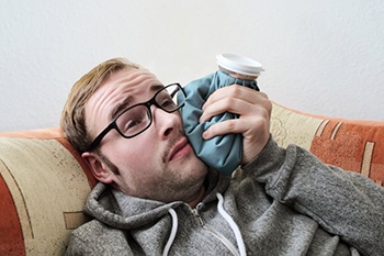 man lying down and holding ice pack to his face