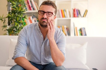 man with a failed dental implant in Columbia, TN holding his cheek in pain