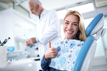 woman smiling in dental chair after receiving tooth-colored fillings