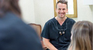Dentist smiling while talking to patients