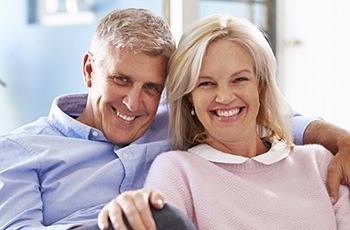 Senior couple smiling together after dental crowns and full mouth reconstruction