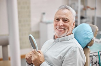 Man checking smile in mirror after bone grafting in Columbia, TN
