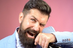 bearded man opening a bottle with his teeth