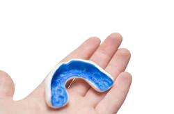 person holding a blue mouthguard in their hand