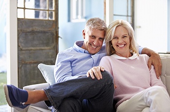 happy couple sitting on their couch after tooth replacement with dental implants