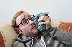 man holding a cold compress to his cheek 