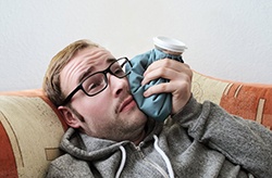 man holding a cold compress to his cheek