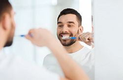 man brushing his teeth in front of a mirror 