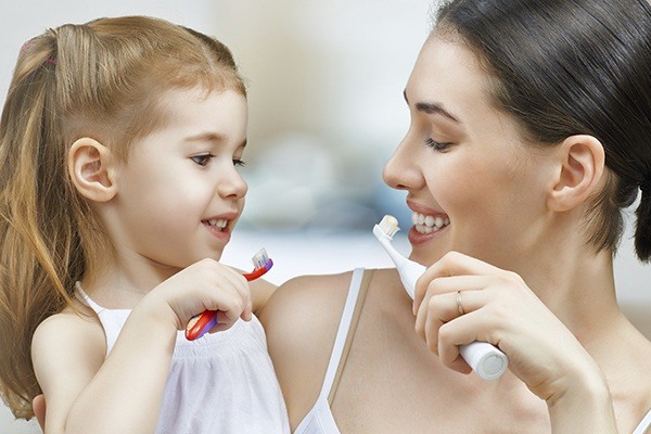 girl and mother brushing teeth