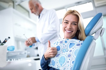 woman giving thumbs up in the dental chair after periodontal therapy