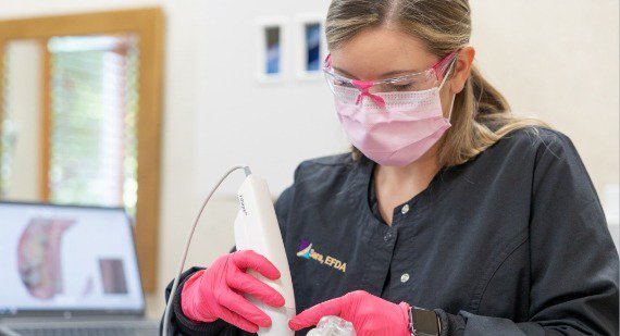 Dental assistant talking to child in exam chair