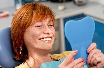 Woman looking at her smile after full mouth reconstruction