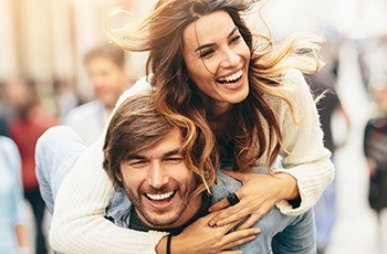 Smiling man and woman outdoors after tooth colored fillings