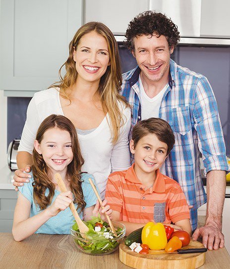 Family smiling and cooking dinner together