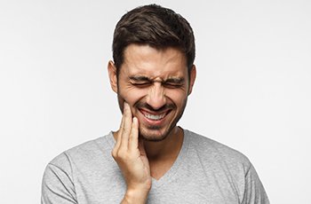 Man holding jaw in pain before T M J therapy