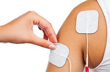 Doctor placing patches for TENS unit onto person’s arm