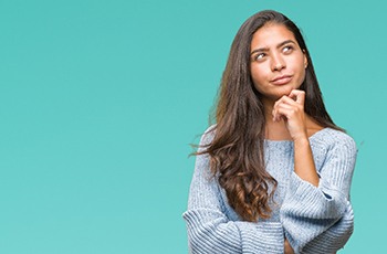 Woman wondering about porcelain veneers in Columbia on blue background