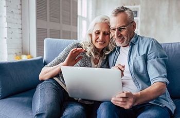 mature couple using laptop to learn about done in one dental implant dentures