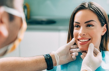 cosmetic dentist looking at patient’s smile 