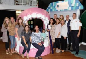 A group of people smiling and posing for a photo with the exhibit.