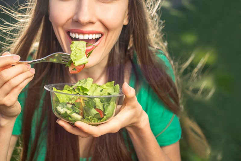 young woman eating salad as instructed by dentist in Columbia