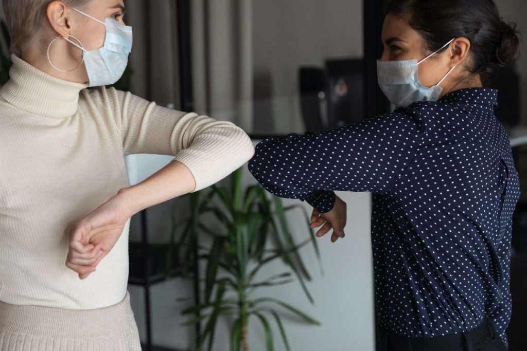 Two women bumping elbows at their dentist in Columbia