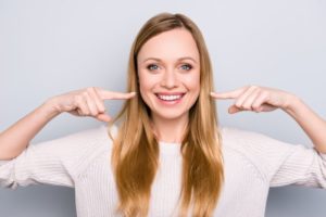 Woman points to her healthy smile after visiting Columbia cosmetic dentist