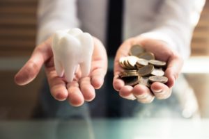 fake tooth in one hand and coins in the other 