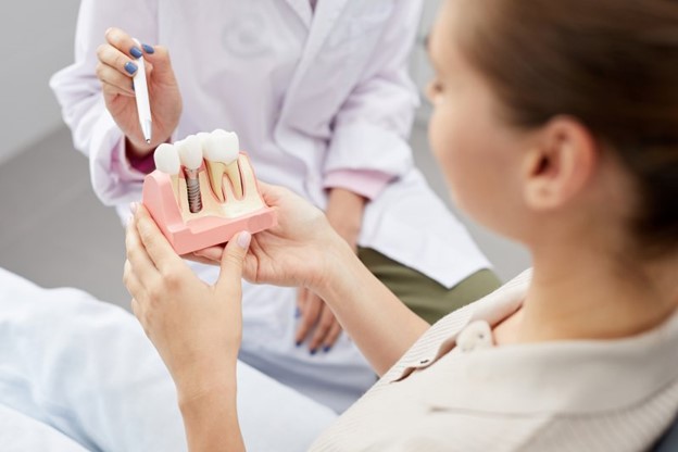 Woman at the dentist holding a model of dental implants.