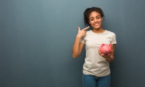 woman holding piggy bank and pointing to her smile