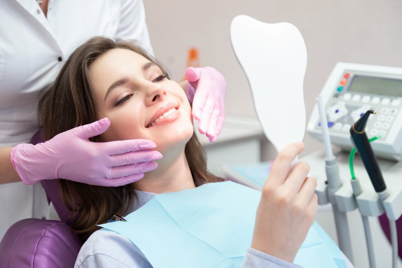 A woman smiling after seeing her new dental veneers for the first time